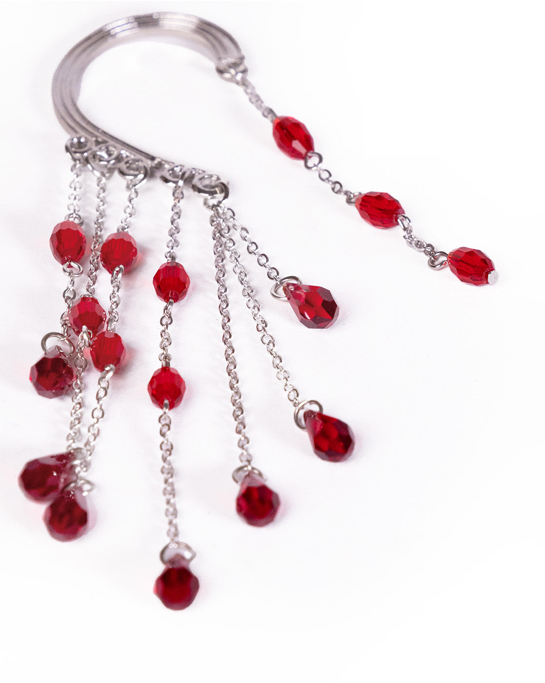 The Red Beads Ear Cuff (left ear) features multiple dangling chains with red crystal beads, displayed on a white background. This metallic ear cuff brings an elegant touch to any look.