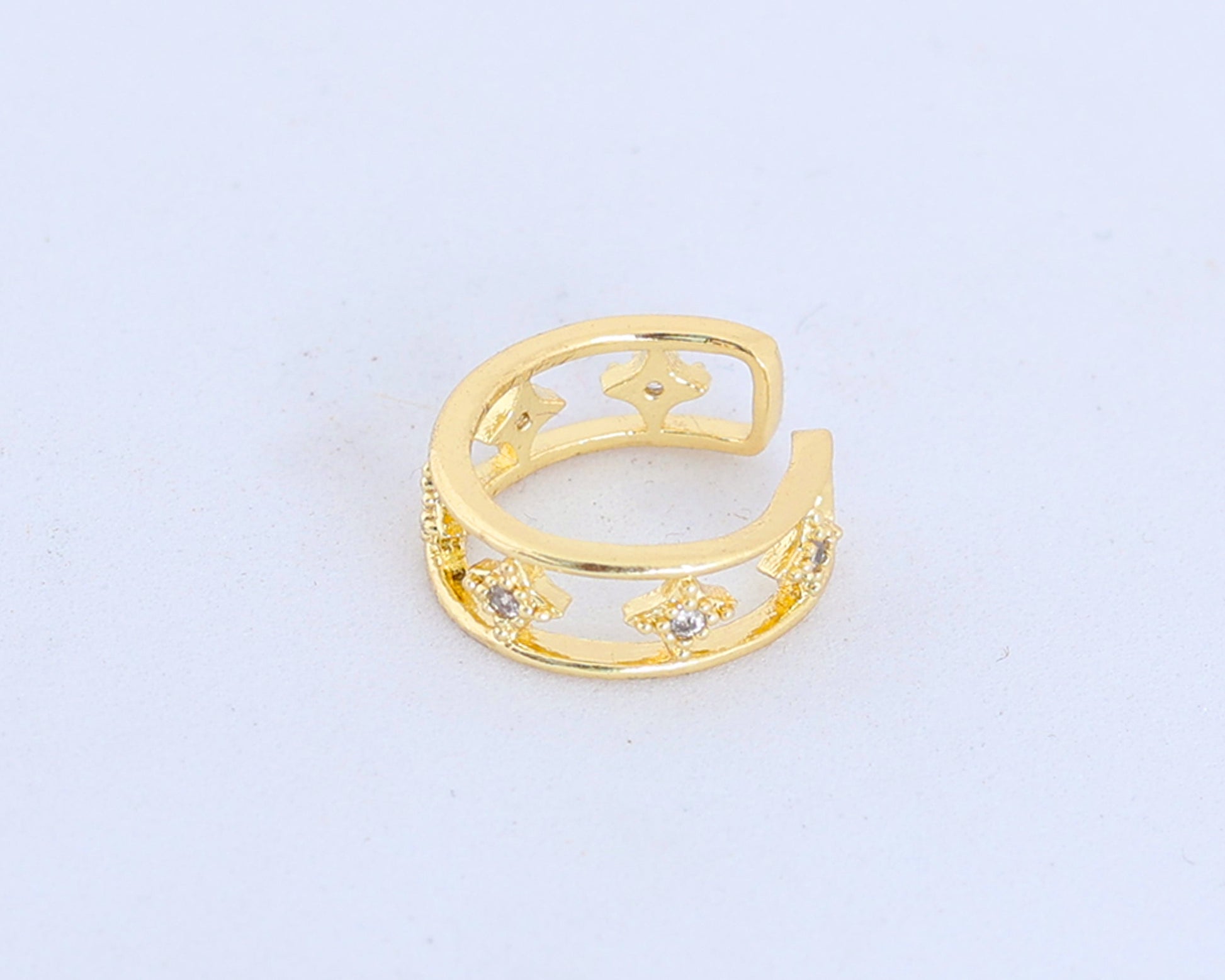 The Small Gold Ear Cuff is gold plated with an open design, featuring star-shaped cutouts and lab-created stones, shown on a plain white background.