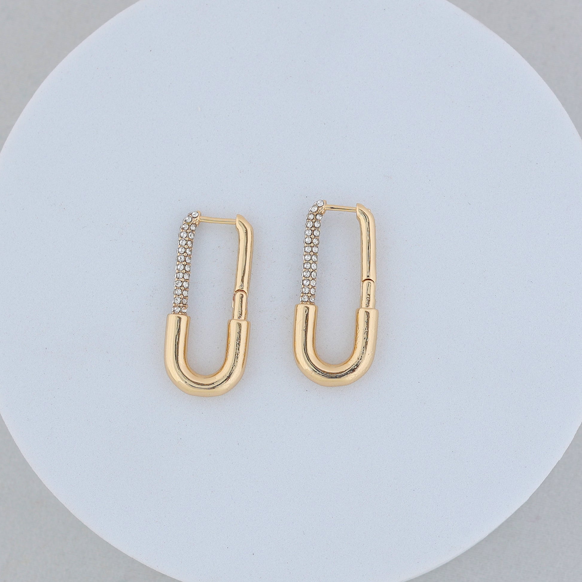 Long Rectangle Gold Hoops with rounded edges, each adorned with a row of sparkling zircon stones on one side, displayed against a white circular background.