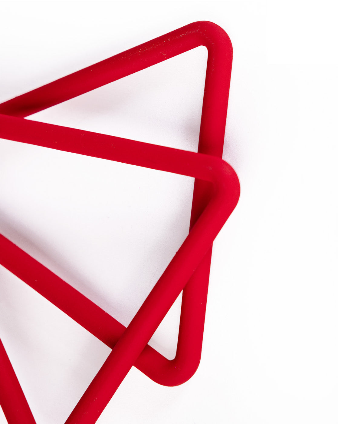 A close-up of intersecting red triangles on white echoes the sleek, affordable luxury of Triangle Earrings, with partially visible shapes forming an abstract geometric pattern.