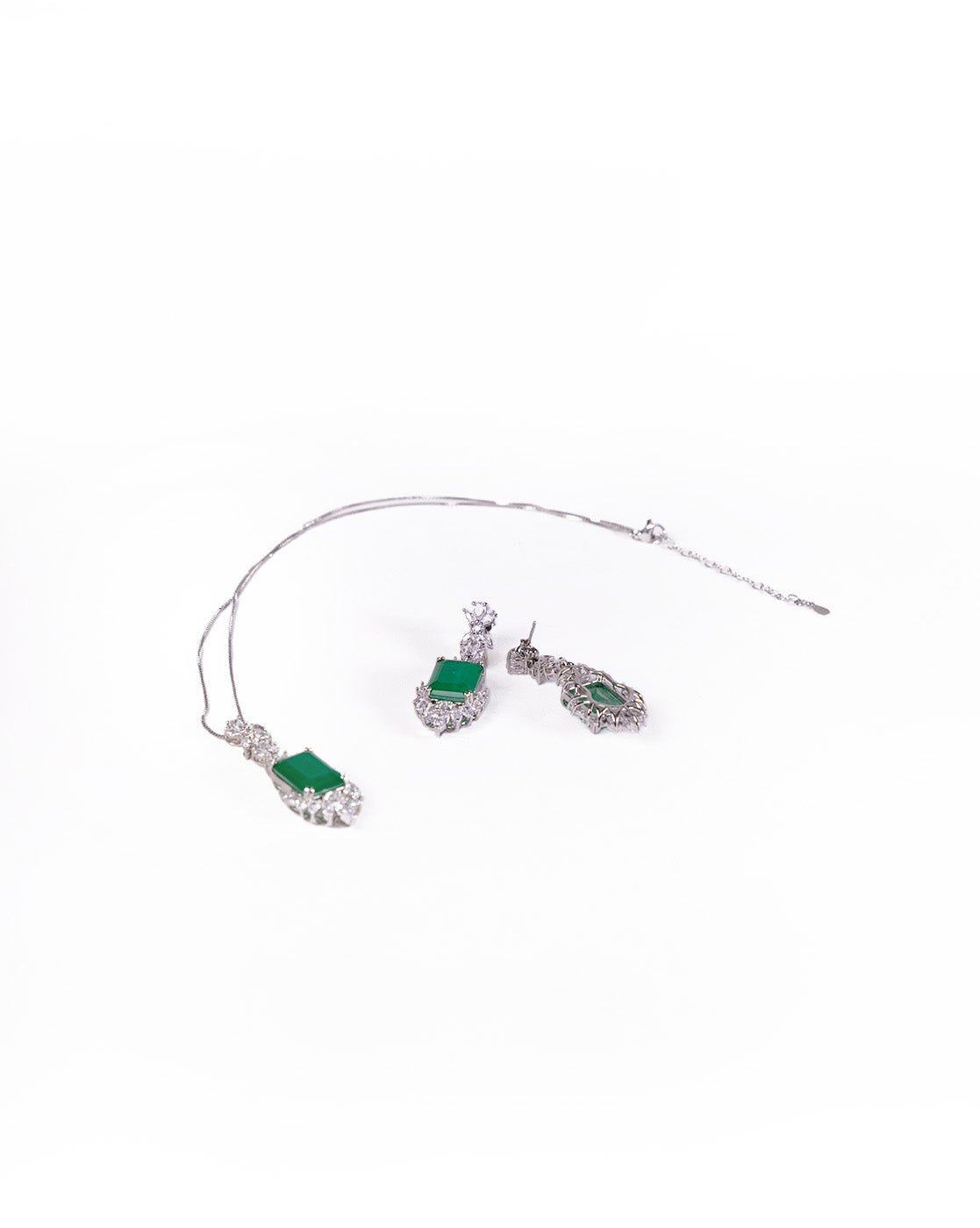 The Queen’s Earrings Set is a silver jewelry set with a green stone necklace and matching earrings, each featuring rectangular gemstones and intricate silver detailing, displayed on a white background.
