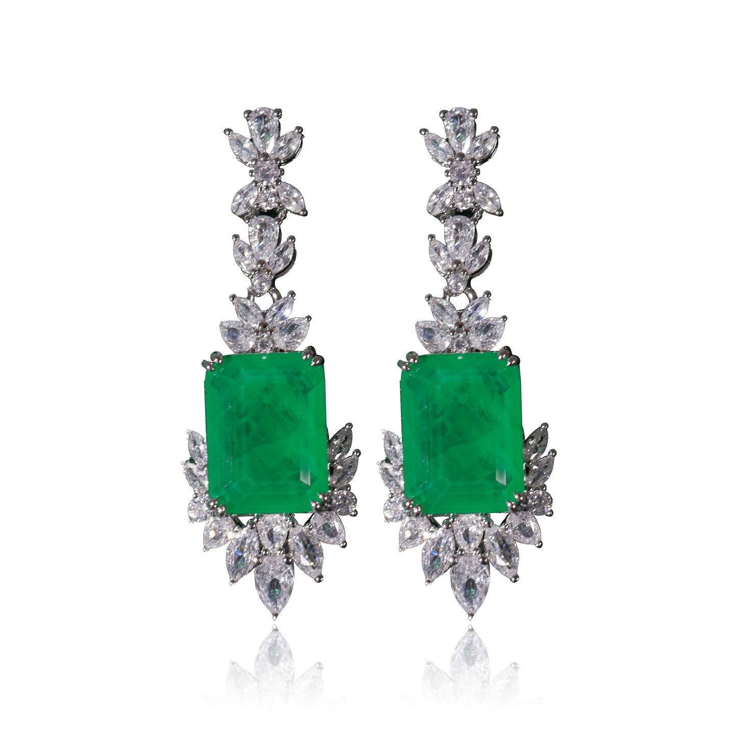 The Queen’s Earrings Set features elegant drop earrings with large rectangular green gemstones, accented by marquise-cut and round white stones, all set in silver metal.
