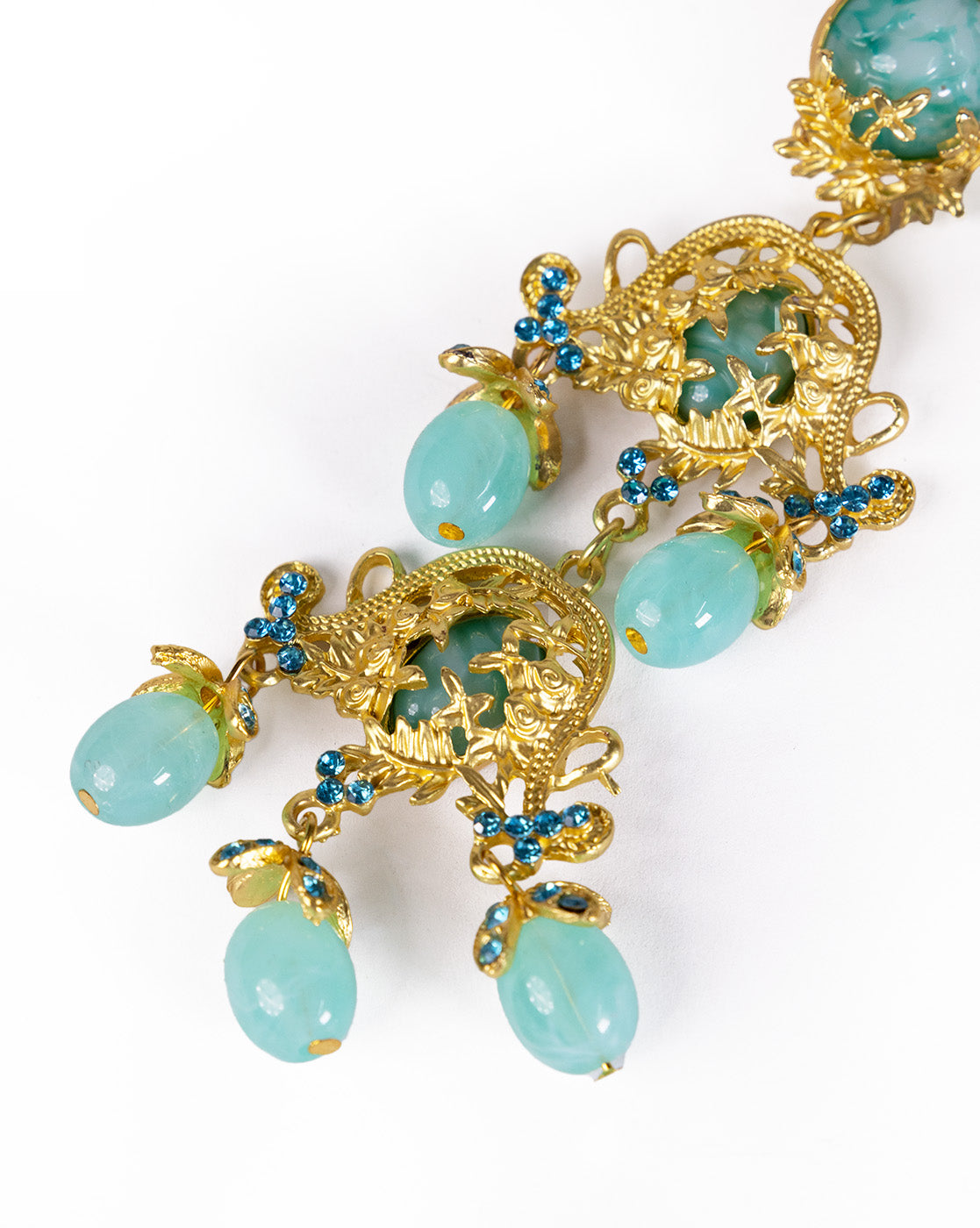 The Resin Water Drop Tassel Danglers feature vintage-inspired blue-green oval stones, small blue rhinestones, and detailed floral and leaf designs for a striking sea green look on a white base.