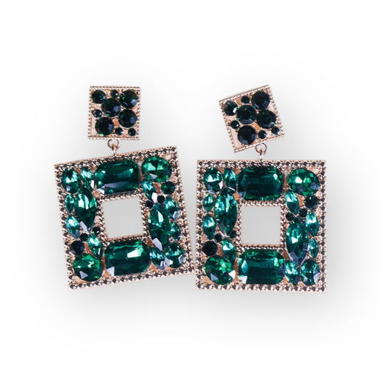 The Green Goblin Earrings are gold plated statement earrings with a square stud and an offset rectangle, both adorned with green and blue gemstones and bordered by small clear stones.